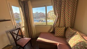Una habitación con sofá, sillón y ventana con cortinas.