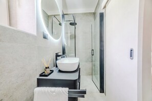 Une salle de bain moderne avec un grand lavabo blanc, une douche en verre et un porte-serviettes.