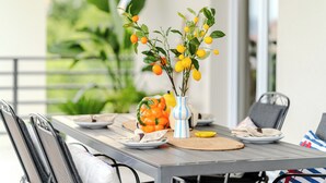 Une table à manger dressée avec des assiettes, des couverts et un vase rempli de fleurs jaunes.