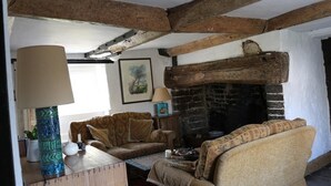 Una sala rústica con vigas de madera a la vista, chimenea y asientos cómodos.