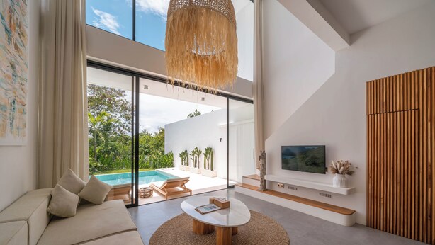 A modern living room with a sofa, a coffee table, and a TV on a wooden wall. - Villa Finity B (Canggu)