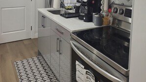 Een moderne keuken met een magnetron, koffiezetapparaat en oven.