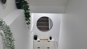 Een trap met een witte muur, een ronde spiegel en een wit dressoir met lades.