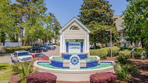 A water feature with a sign reading 'Waterway Landing' surrounded by landscaped greenery. - Waterway Haven (North Myrtle Beach)