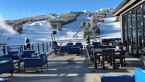 A ski resort's outdoor seating area with a view of a snowy mountain slope. - SKI IN/OUT RESORT AT BRECKENRIDGE - GRAND COLORADO ON PEAK EIGHT 
CHRISTMAS TIME (Breckenridge)