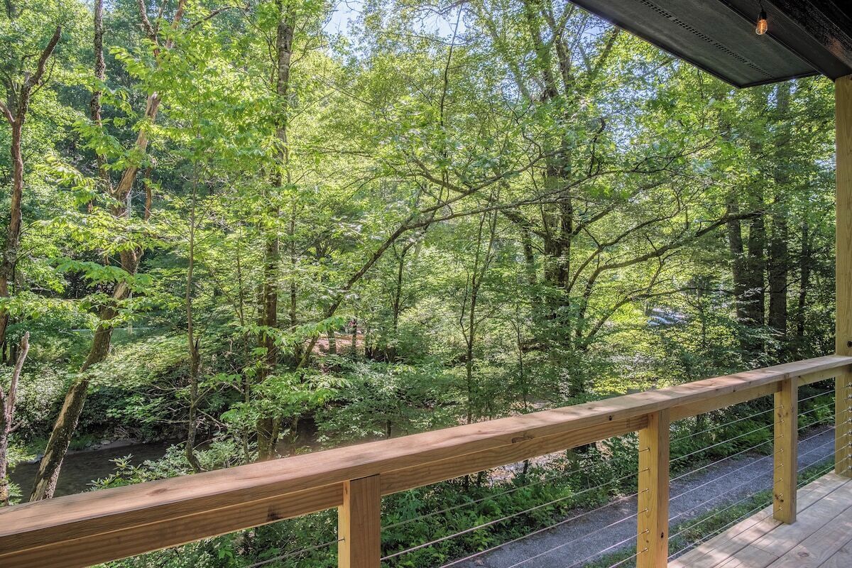 Una terraza de madera con vistas a un área boscosa y un arroyo.