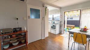 A kitchen with a wooden cabinet, a white door, and a dining area with yellow chairs. - ◇◇NO CLEANING FEE◇◇
Cottage135 Rotorua - Family-friendly holiday home (Rotorua)