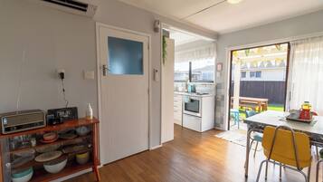 A kitchen with a wooden cabinet, a white door, and a dining area with yellow chairs.