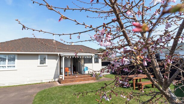 A single-story house with a porch, a lawn, and a tree with pink blossoms. - ◇◇NO CLEANING FEE◇◇
Cottage135 Rotorua - Family-friendly holiday home (Rotorua)