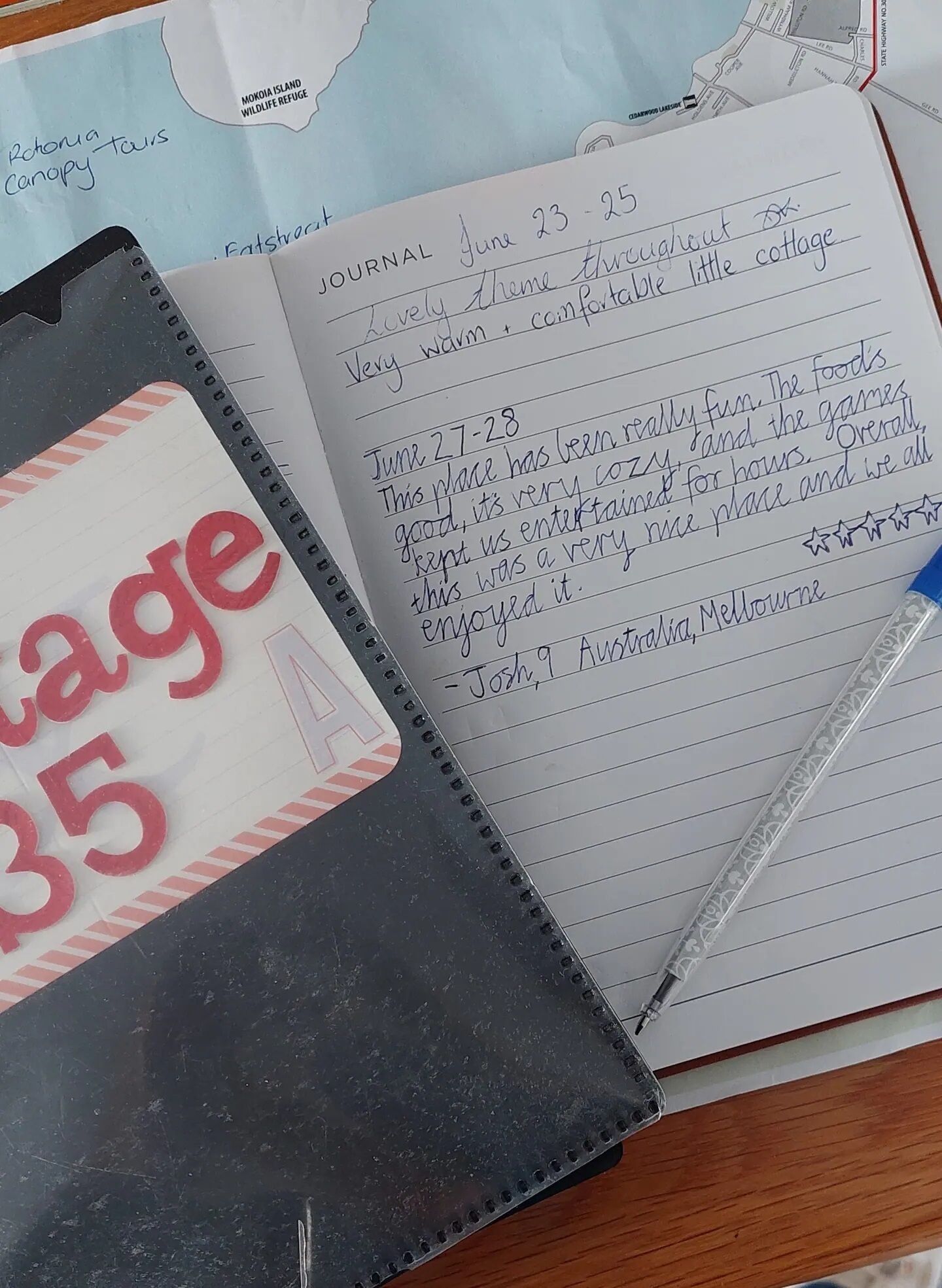 A notebook with handwritten entries dated June 23-25, detailing a visit to a place described as a lovely theme throughout, very warm, and comfortable little cottage.