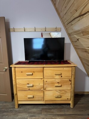 Rustic dresser with smart TV and coat hooks in cozy cabin bedroom