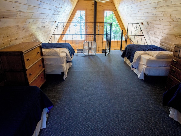 Une chambre avec deux lits, un plafond en bois et une fenêtre.