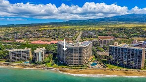 A coastal resort area with multiple high-rise buildings, a beach, and a mountainous backdrop.