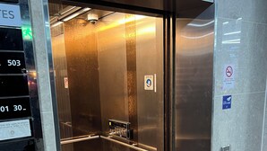 Un ascenseur doté d’un intérieur métallique, d’un écran numérique et d’une barre de maintien.