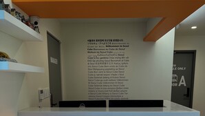 Le Jongno Seoul Cube Hotel dispose d’un comptoir d’accueil au design moderne, caractérisé par une combinaison de couleurs vives, notamment l’orange et le blanc.