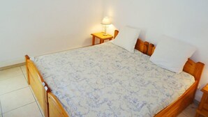 Une chambre à coucher avec un lit en bois, une table de chevet avec une lampe et un tableau encadré au mur.