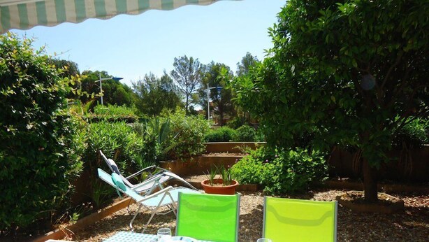 Un espace de restauration en plein air avec une nappe à carreaux, deux chaises et une petite table dressée pour deux personnes.