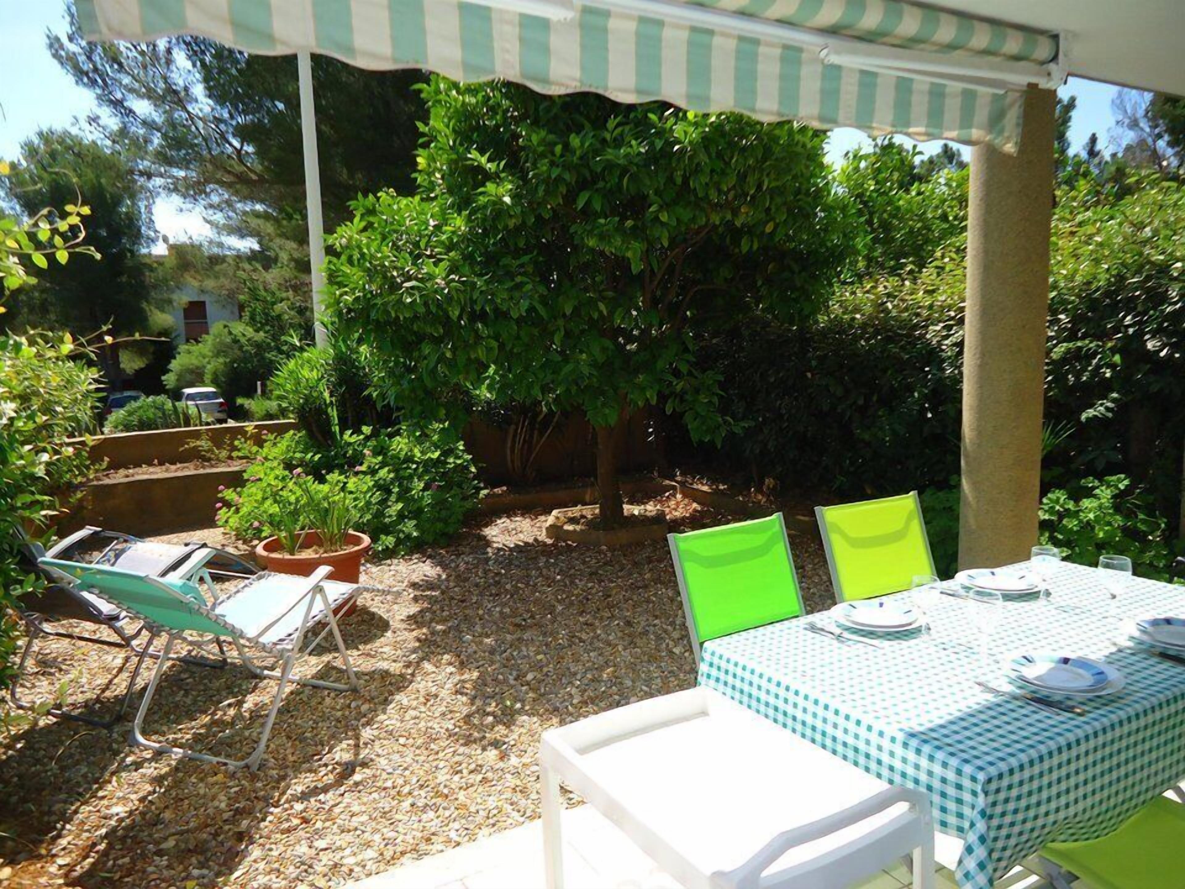 An outdoor patio with a checkered tablecloth, two chairs, and a covered seating area.
