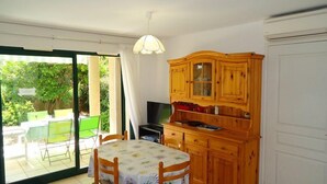 Un coin repas avec une table et des chaises, un téléviseur et des meubles de rangement en bois.