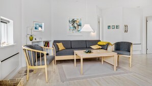 A modern living room with a grey sofa, wooden coffee table, and a floor lamp. - Gudhjem Søpark Lejl. 24 (Gudhjem)