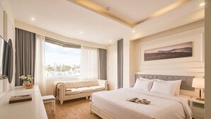 A hotel room with a large bed, a sofa, a desk, and a window with curtains. - Nature Hotel - Pham Hong Thai (Xuan Huong - Da Lat)