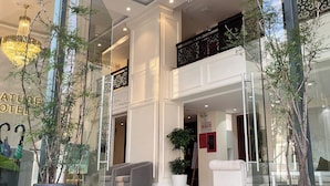A hotel lobby with a glass entrance, modern chandeliers, and potted plants. - Nature Hotel - Pham Hong Thai (Xuan Huong - Da Lat)