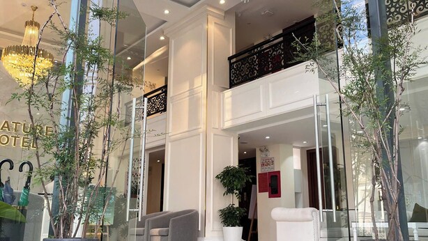 A hotel lobby with a glass entrance, modern chandeliers, and potted plants. - Nature Hotel - Pham Hong Thai (Xuan Huong - Da Lat)