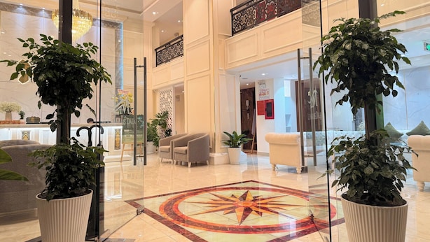 A spacious lobby with a central geometric floor design, large potted plants, and a modern chandelier. - Nature Hotel - Pham Hong Thai (Xuan Huong - Da Lat)