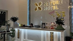 A reception desk with a chandelier, a sign reading 'Nature Hotel,' and a potted plant. - Nature Hotel - Pham Hong Thai (Xuan Huong - Da Lat)