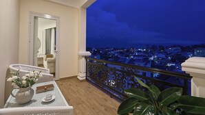 A balcony with a city view at night, a white table with a vase of flowers, and a chair. - Nature Hotel - Pham Hong Thai (Xuan Huong - Da Lat)