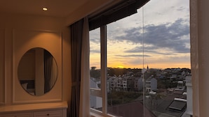 A room with a large window, a round mirror, a tufted chair, and a small table. - Nature Hotel - Pham Hong Thai (Xuan Huong - Da Lat)