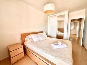 A bedroom with a wooden bed, a bedside table, and a mirror.