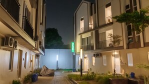 A courtyard with a covered seating area, a sign for 'F. Monico', and buildings with balconies and windows. - Mono Coliving at BSD City (Pagedangan)