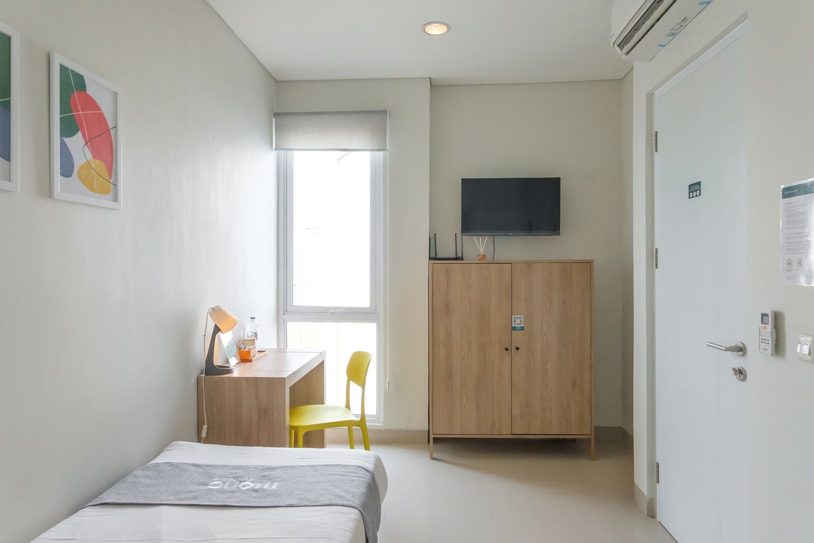 Ein Schlafzimmer mit einem Bett, einem Schreibtisch, einem Stuhl, einem Kleiderschrank und einem Fernseher.