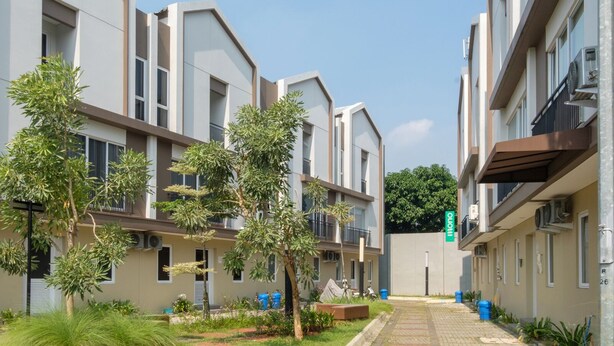 A modern apartment building with balconies, a garden area, and a clear sky. - Mono Coliving at BSD City (Pagedangan)