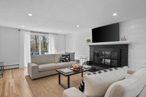 Ein modernes Wohnzimmer mit Kamin, einer Couch, einem Couchtisch und einem Fernseher.