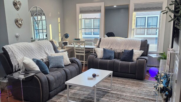 Un salon moderne avec un canapé gris, une table basse blanche et un tapis à rayures.