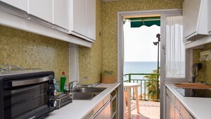 A compact kitchen with a built-in toaster oven, a sink, and a view of the sea through an open door. - Ref: 326 Beach front apartment on the promenade with beautiful sea view (Fuengirola)