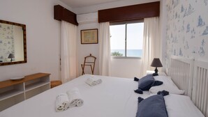 A hotel room with two beds, a wooden chair, a desk with a lamp, and a large window with a view of the sea. - Ref: 326 Beach front apartment on the promenade with beautiful sea view (Fuengirola)