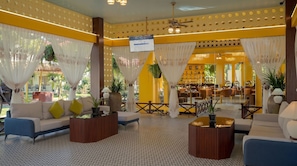 A hotel lobby with a check-in counter, seating area, and a view of the outdoor garden. - Habana Angkor Resort (Siem Reap)