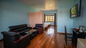 A hotel room with a sofa, a small table with books, a bed, a TV, and a window with curtains. - Habana Angkor Resort (Siem Reap)