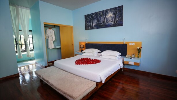 Une chambre d’hôtel avec un lit, une table de chevet, une commode et un tableau au mur.