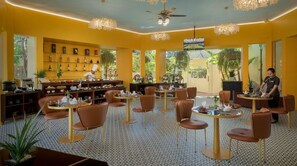 A restaurant with multiple tables and chairs, a chef at the counter, and a bar area with shelves of bottles. - Habana Angkor Resort (Siem Reap)