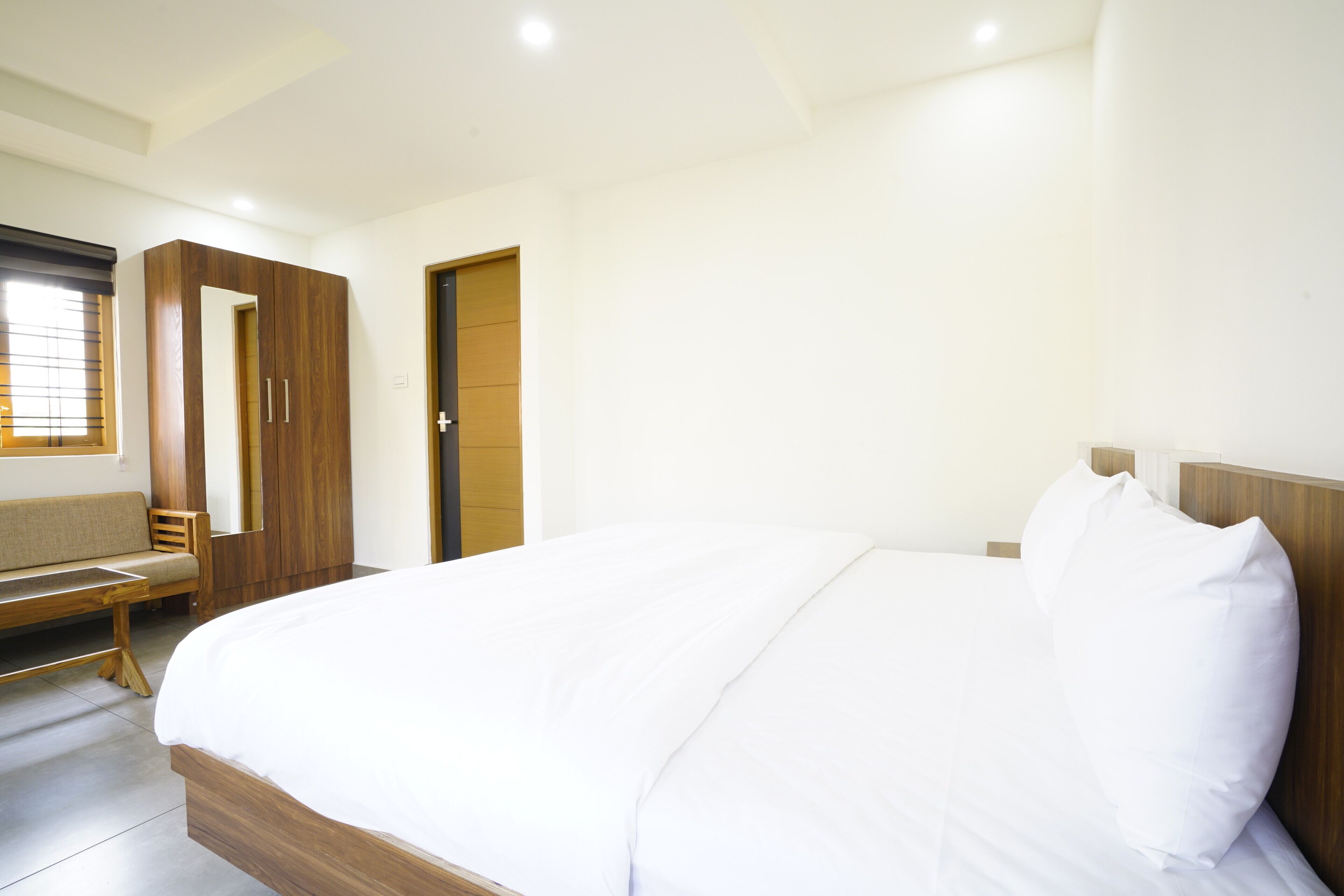 Un dormitorio con una cama grande, un armario de madera, un banco y una puerta.