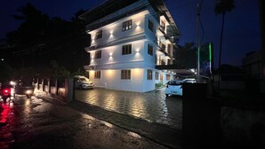 A multi-story building with a well-lit facade and a gated entrance. - Halo Residency (Kanayannur)
