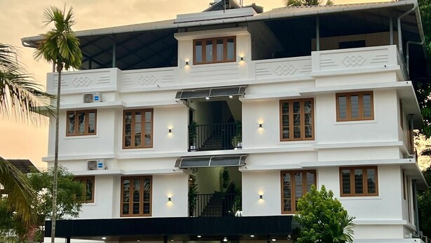 A multi-story building with a white facade, multiple balconies, and a central staircase. - Halo Residency (Kanayannur)