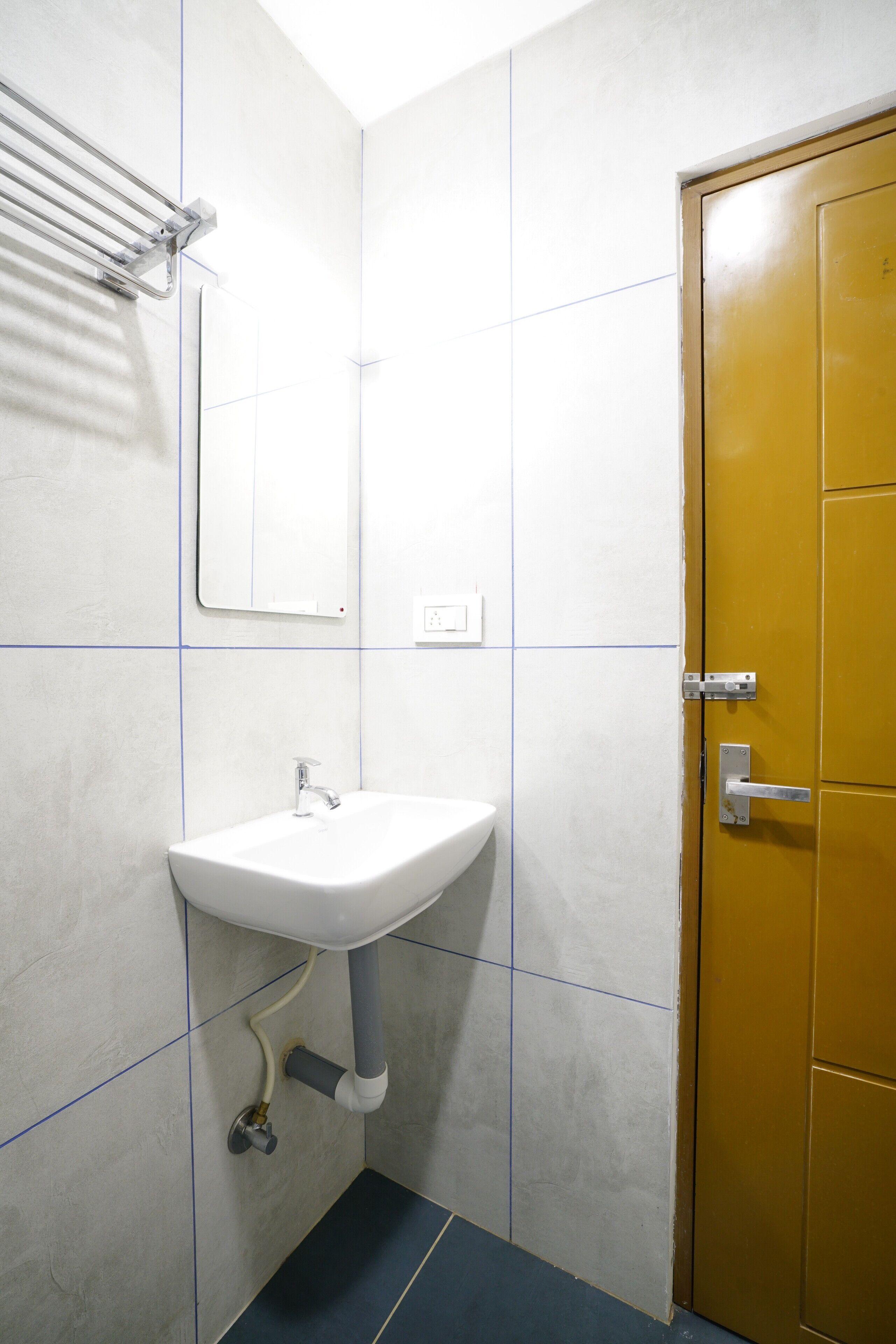 A bathroom with a white sink, a mirror, and a yellow door.