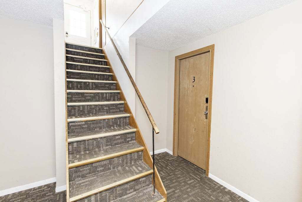A staircase with a wooden handrail leading to a door marked with the number 3.