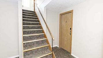 A staircase with a wooden handrail leading to a door marked with the number 3.