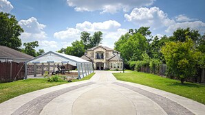 Une grande maison avec une allée menant à un patio abrité.